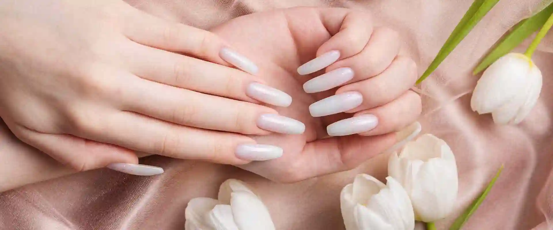 Two white manicured hands with floral background.